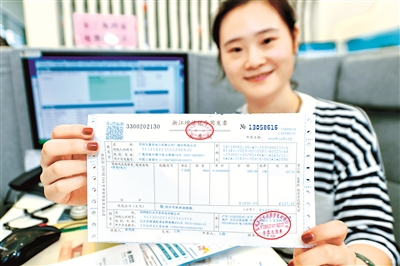 浙江省湖州市长兴供电营业厅,工作人员正在展示刚刚办理的来自安徽广德的电费增值税专用发票。 (图片来源:视觉中国)