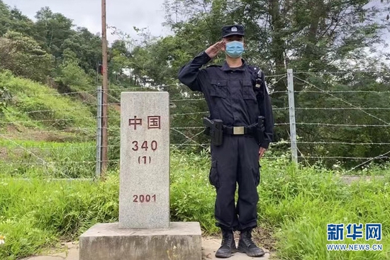 张俊巡逻途中与界碑合影(资料图)新华网发。(天保出入境边防检查站供图)