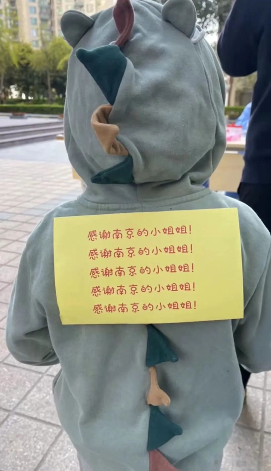 ▲徐家汇街道东方曼哈顿小区,一位小朋友背后贴了写有感谢南京医护人员话语的纸条。