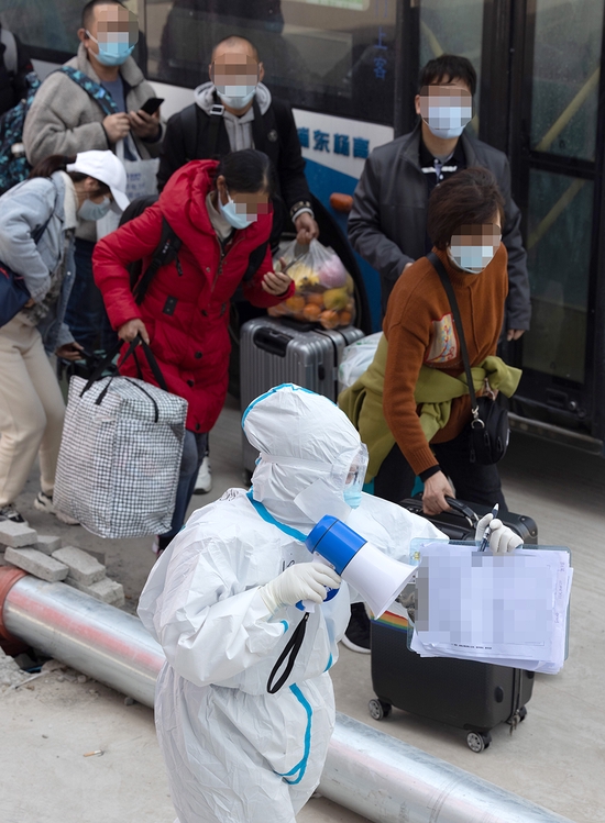 2022年4月6日,上海临港方舱医院,一名工作人员带领一批新转运来的感染者即将入住接受治疗。新华社发(华山医院 供图)
