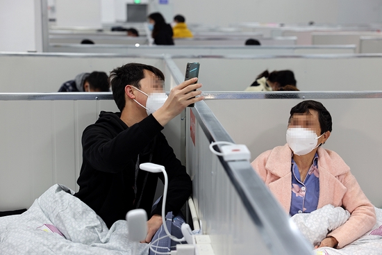 2022年4月6日,在上海临港方舱医院,一对母子在与家人视频聊天。新华社发(华山医院 供图)