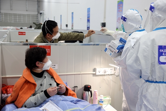 2022年4月6日,在上海临港方舱医院,来自江苏的医护人员在帮感染者查看体温。新华社发(华山医院 供图)
