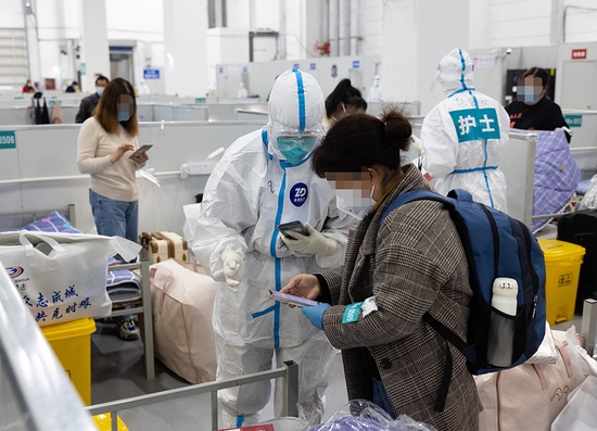 2022年4月6日,在上海临港方舱医院,来自复旦大学附属华山医院的医护人员为新转运过来的感染者安排床位。新华社发(华山医院 供图)