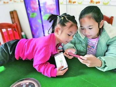 广西金秀县，两名儿童正在玩手机。何鲜桂 摄/光明图片