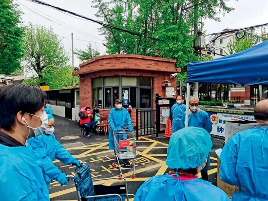 4月14日,华师大二村志愿者再小区大门内等待分发物资。图/受访者提供