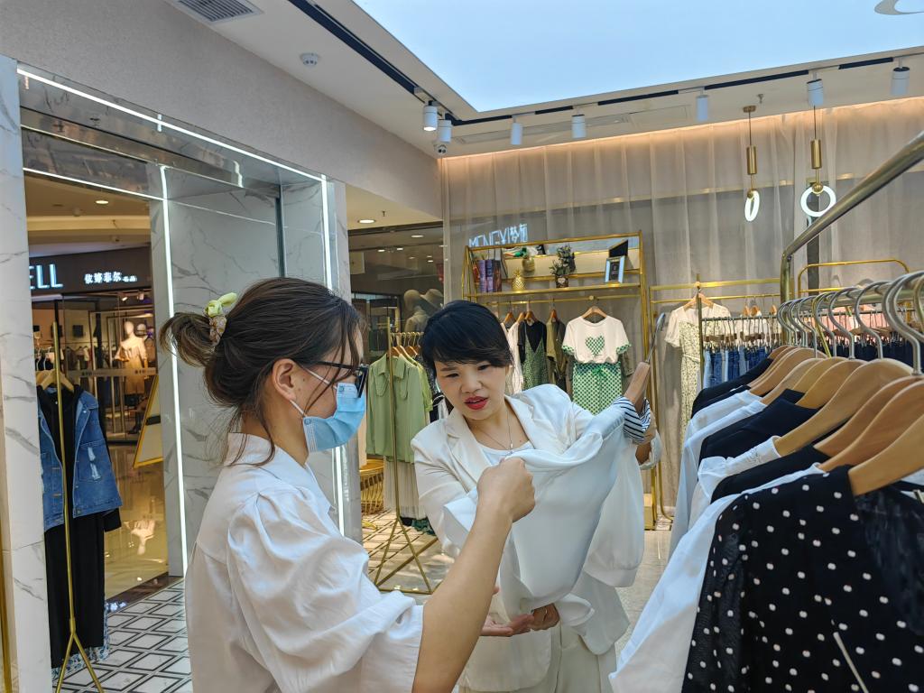 姚亚军(右一)在实体店向顾客介绍产品。新华社记者 张斌 摄