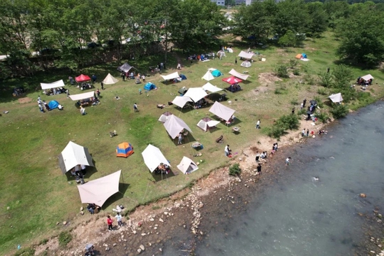 5月3日，游客在浙江省瑞安市湖岭镇天长村溪边搭帐篷露营（无人机照片）。图片来源：新华社发（庄颖昶摄）