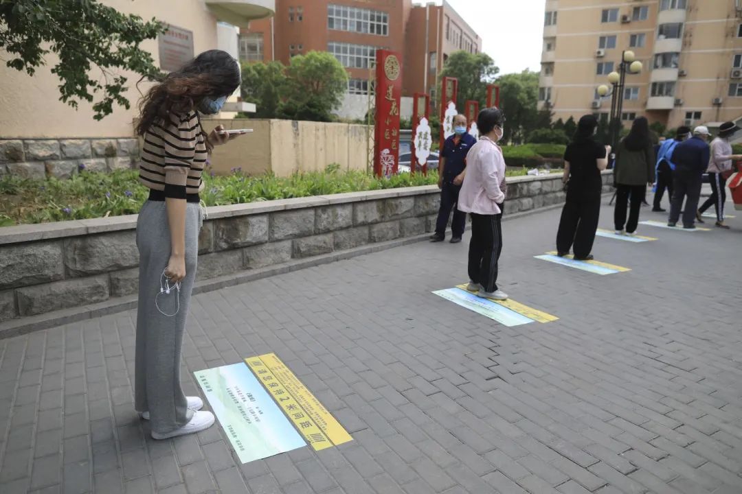 ▲5月5日，海淀区羊坊店街道莲花小区，一位女士在排队时拍摄地上的古诗。  新京报记者 浦峰 摄