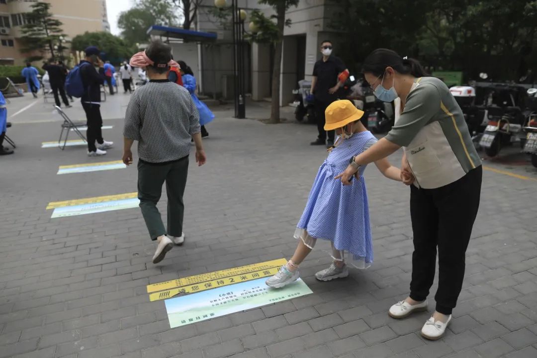 ▲5月5日，海淀区羊坊店街道莲花小区，一位检测完核酸的妈妈带着女儿在读地上的古诗。  新京报记者 浦峰 摄