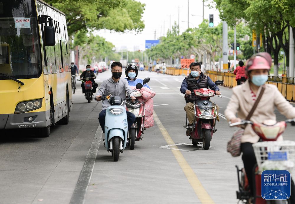 在上海市嘉定区新成路街道,人们骑行在道路上(5月9日摄)。