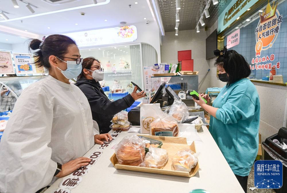 顾客在上海市松江区中山中路的一家面包店购物(5月10日摄)。