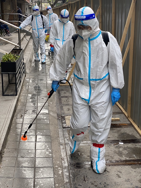 图①上海市虹口区检察院突击队员朱拓程背着16L的消毒水在封控小区开展消杀作业。　本报记者江苏烨　通讯员陈润悦摄