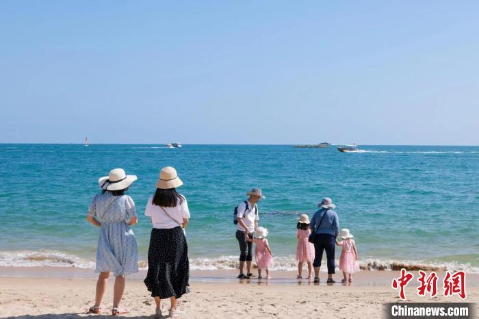 资料图：家长带着孩子在海边嬉浪。　游建行 摄