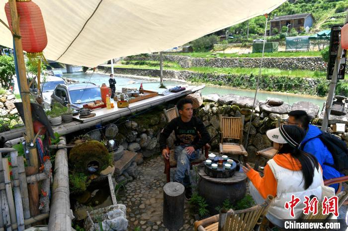 村民和游客喝茶聊天。　吕明 摄