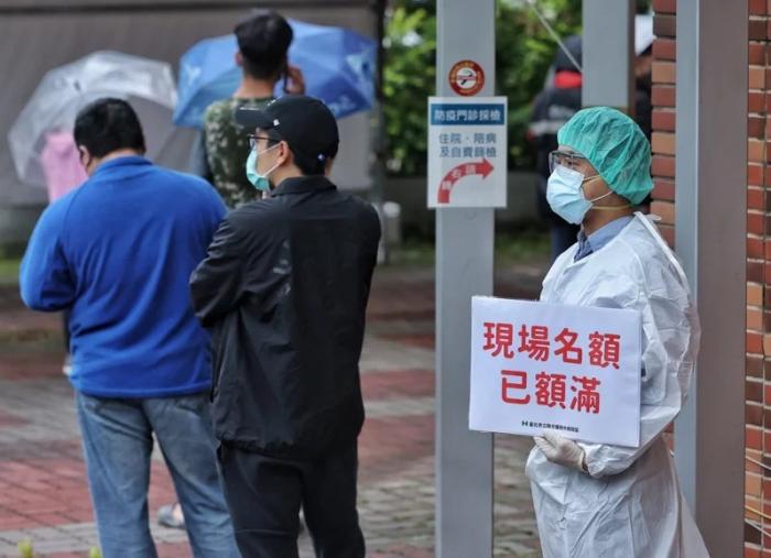 资料图:台湾快筛站现场名额额满,医护人员于排队末端举牌提醒。图片来源:台湾《联合报》,记者 曾原信 摄