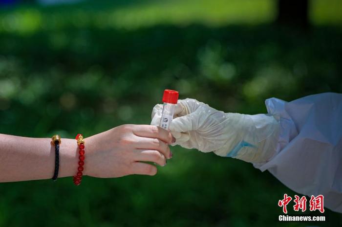 图为5月22日,一位北京市民将自己的病毒采样管交给采样人员。 中新社记者 贾天勇 摄